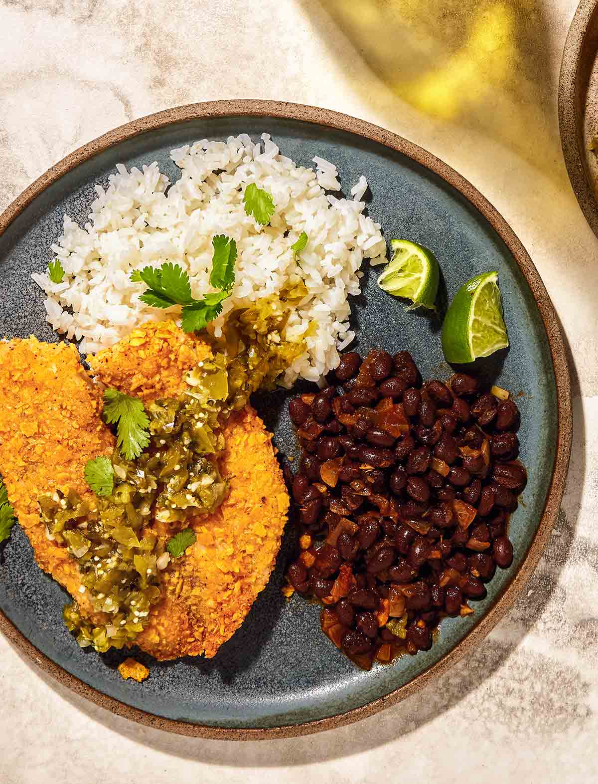 Air fryer tilapia with tortilla crust on a plate with rice and beans