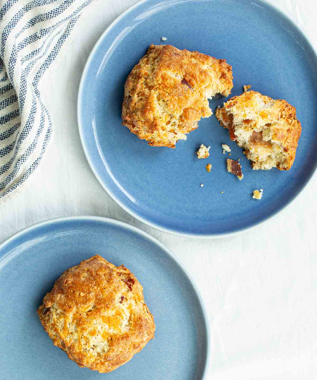 Two blue plates with bacon cheddar scones divided between them.
