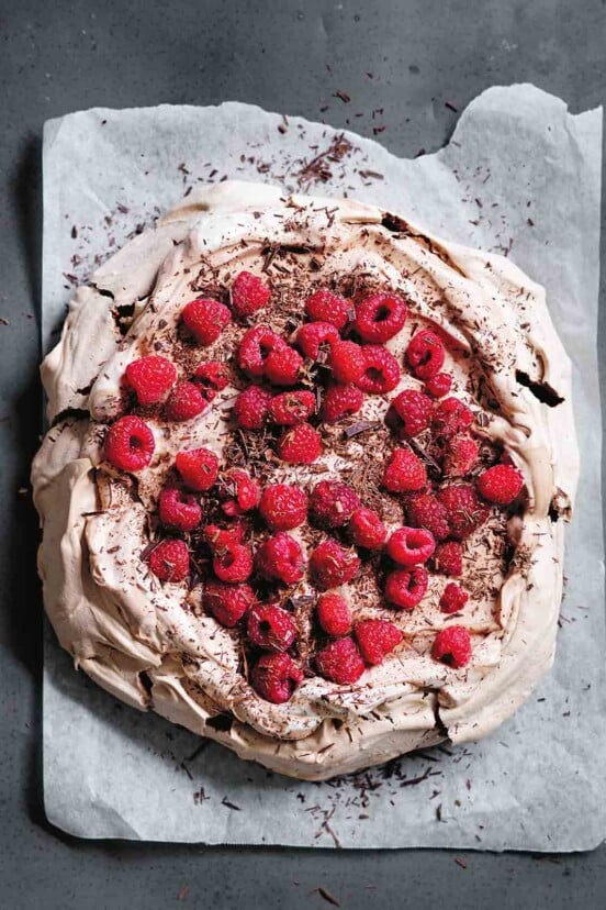 A chocolate pavlova with raspberries on parchment paper
