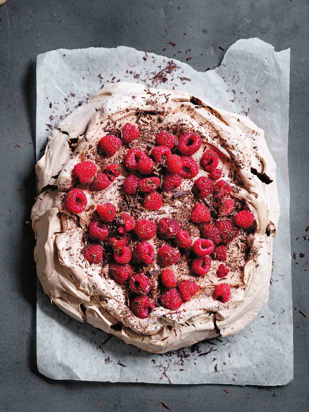 A chocolate pavlova with raspberries on parchment paper