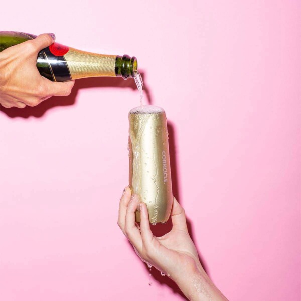 Corkcicle Champagne Cup pink background with champangne being poured in.
