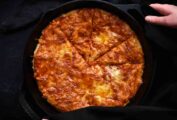 An easy skillet pizza for kids in the pan being held by a woman's hands