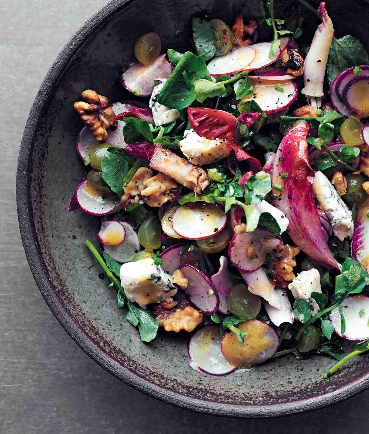 Endive Roquefort salad in a blue speckled bowl, garnished with walnuts.