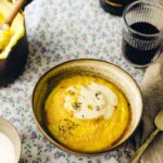 An earthenware bowl filled with Friulian polenta and topped with cheese sauce and black pepper.