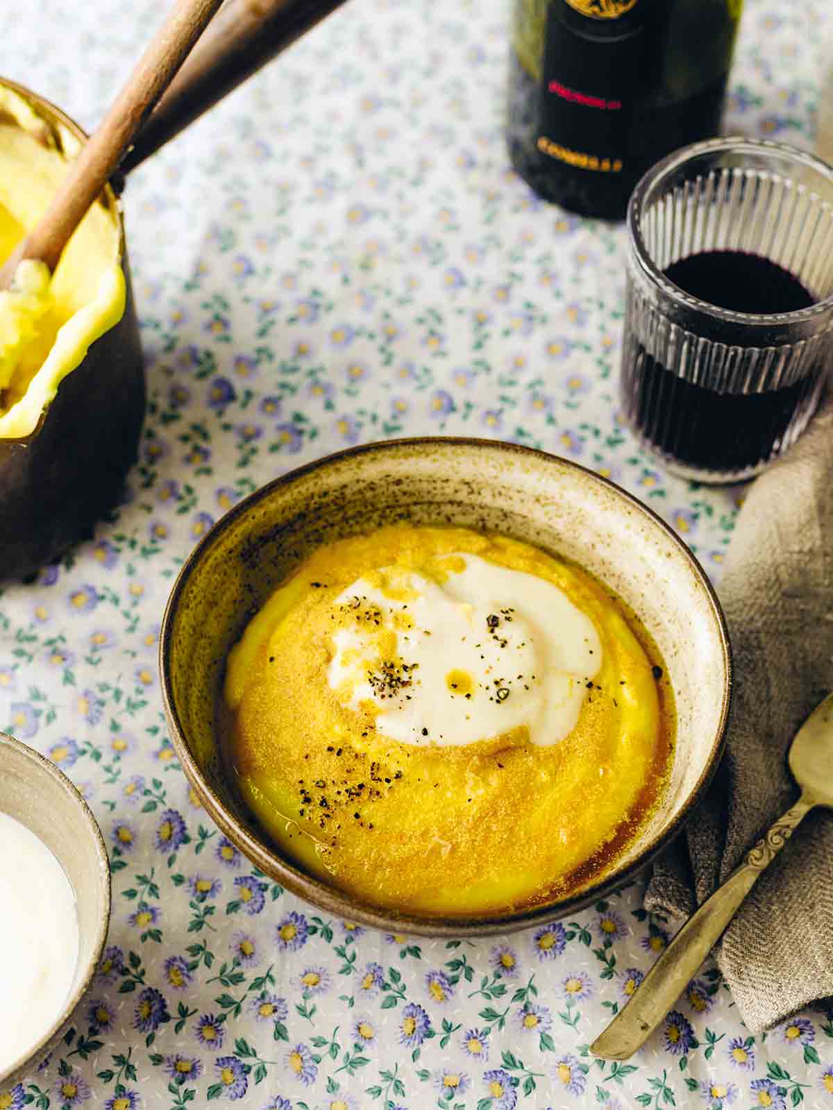 En skål i lergods fylld med friulisk polenta och toppad med ostsås och svartpeppar.