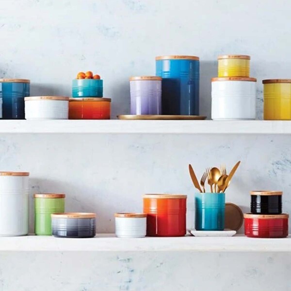 Le Creuset 1.5-Quart Stoneware Canister with Wood Lid multi colored canisters on shelves.