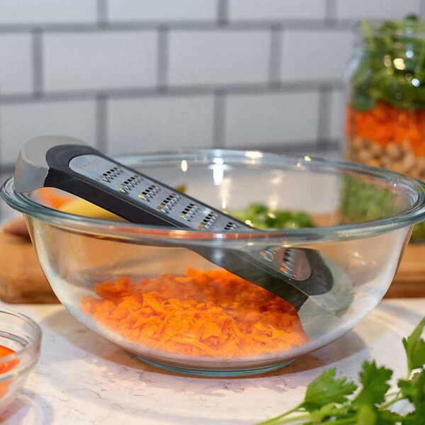 Side view of Microplane Mixing Bowl Grater in glass bowl with carrots.