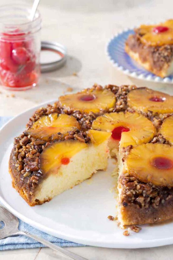 A pineapple upside-down cake on a white plate with a slice taken out