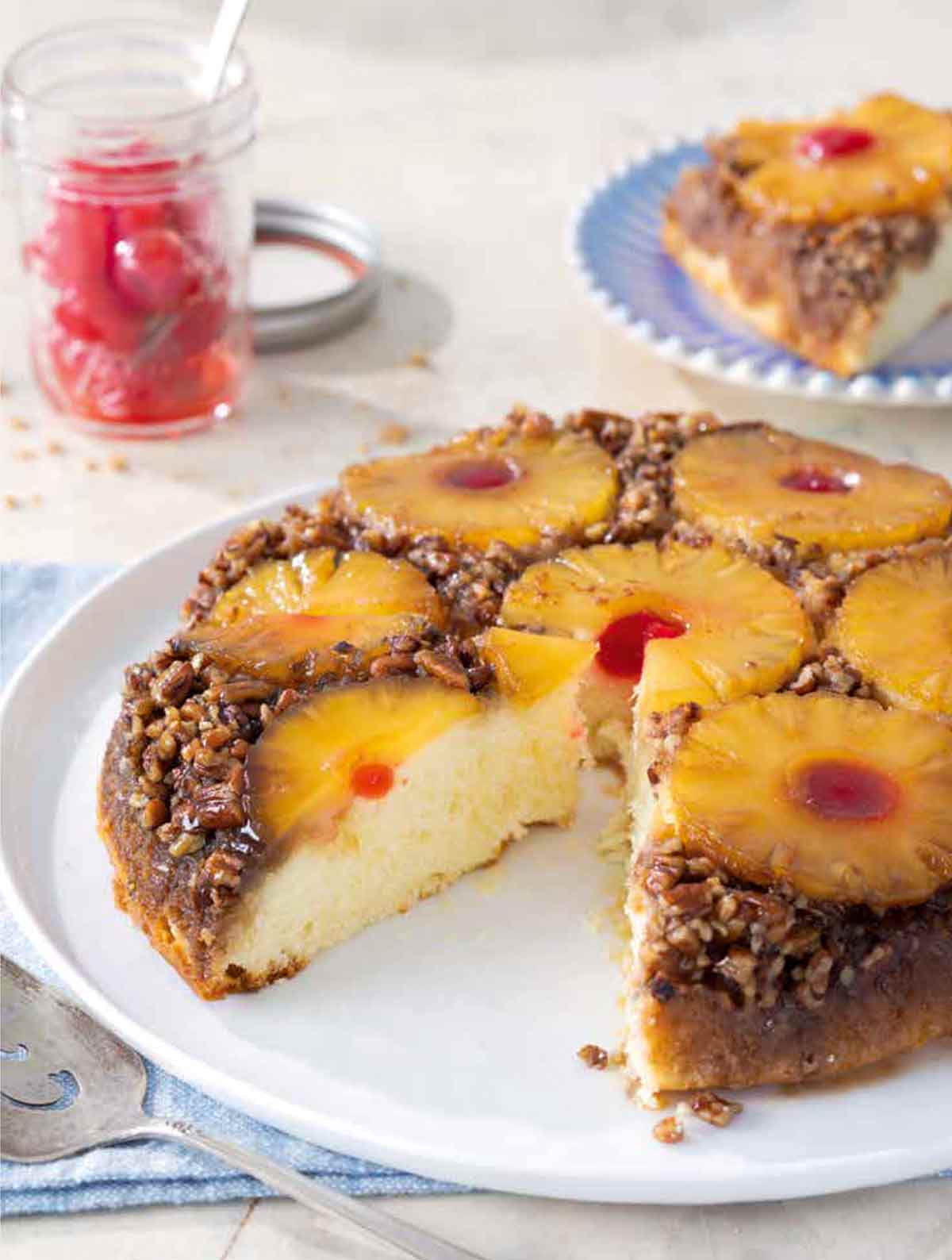 A pineapple upside-down cake on a white plate with a slice taken out