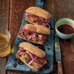 Three slow cooker French dip sandwiches on a cutting board