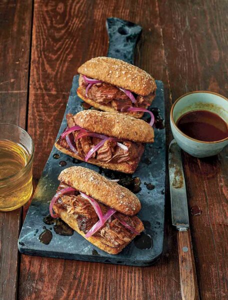 Three slow cooker French dip sandwiches on a cutting board