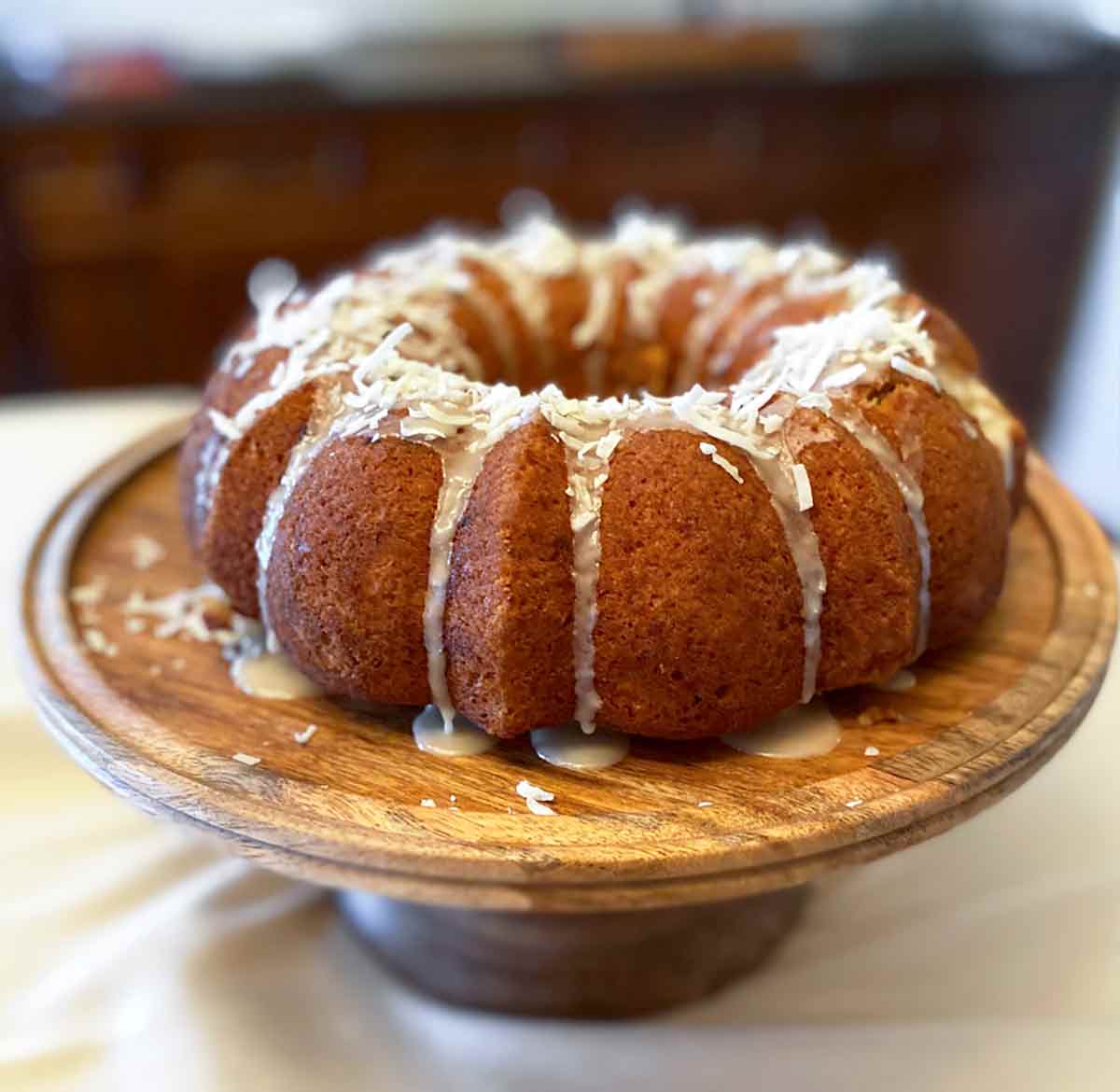 A banana coconut rum bundt cake on a wooden cake stand.