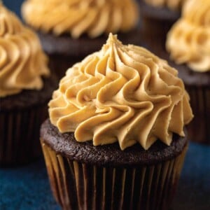 Several chocolate cupcakes with peanut butter buttercream frosting piped on top.