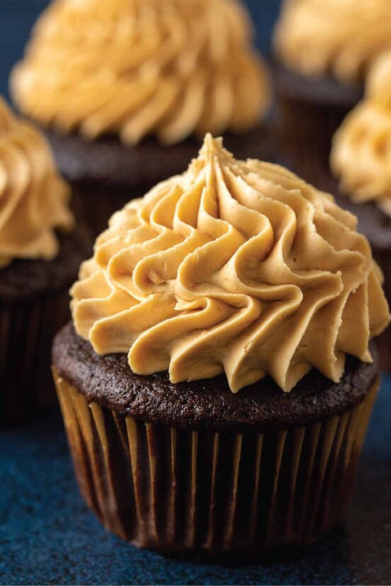 Several chocolate cupcakes with peanut butter buttercream frosting piped on top.