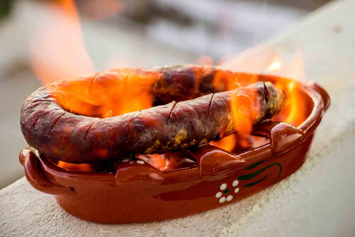 A ceramic holder with a link of chouriço a bombeiro, or fireman's sausage on fire inside