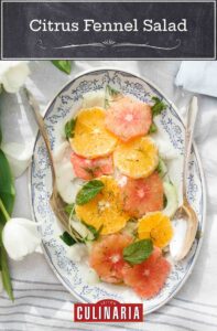 A citrus fennel salad assembled on a white and blue serving platter, topped with fresh herbs.
