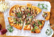An oval flatbread with pancetta, pear, and blue cheese, cut into 10 wedges.