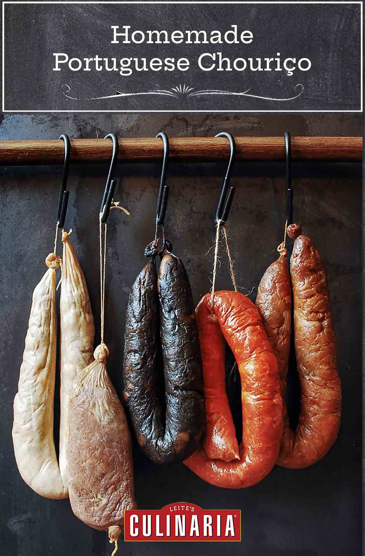 Five links of common Portuguese sausages, including homemade chouriço, hanging from hooks on a wooden dowel