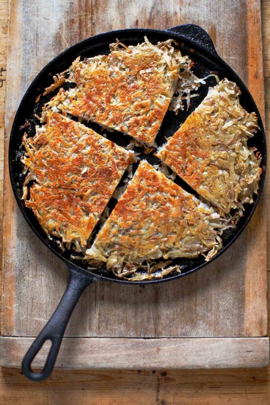 Cast iron skillet with a pan boxty(Irish potato pancake) in it, on a wooden cutting board