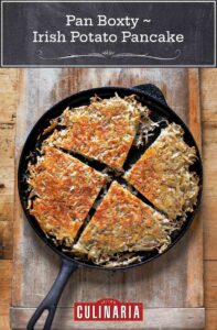 Cast iron skillet with a pan boxty(Irish potato pancake) in it, on a wooden cutting board
