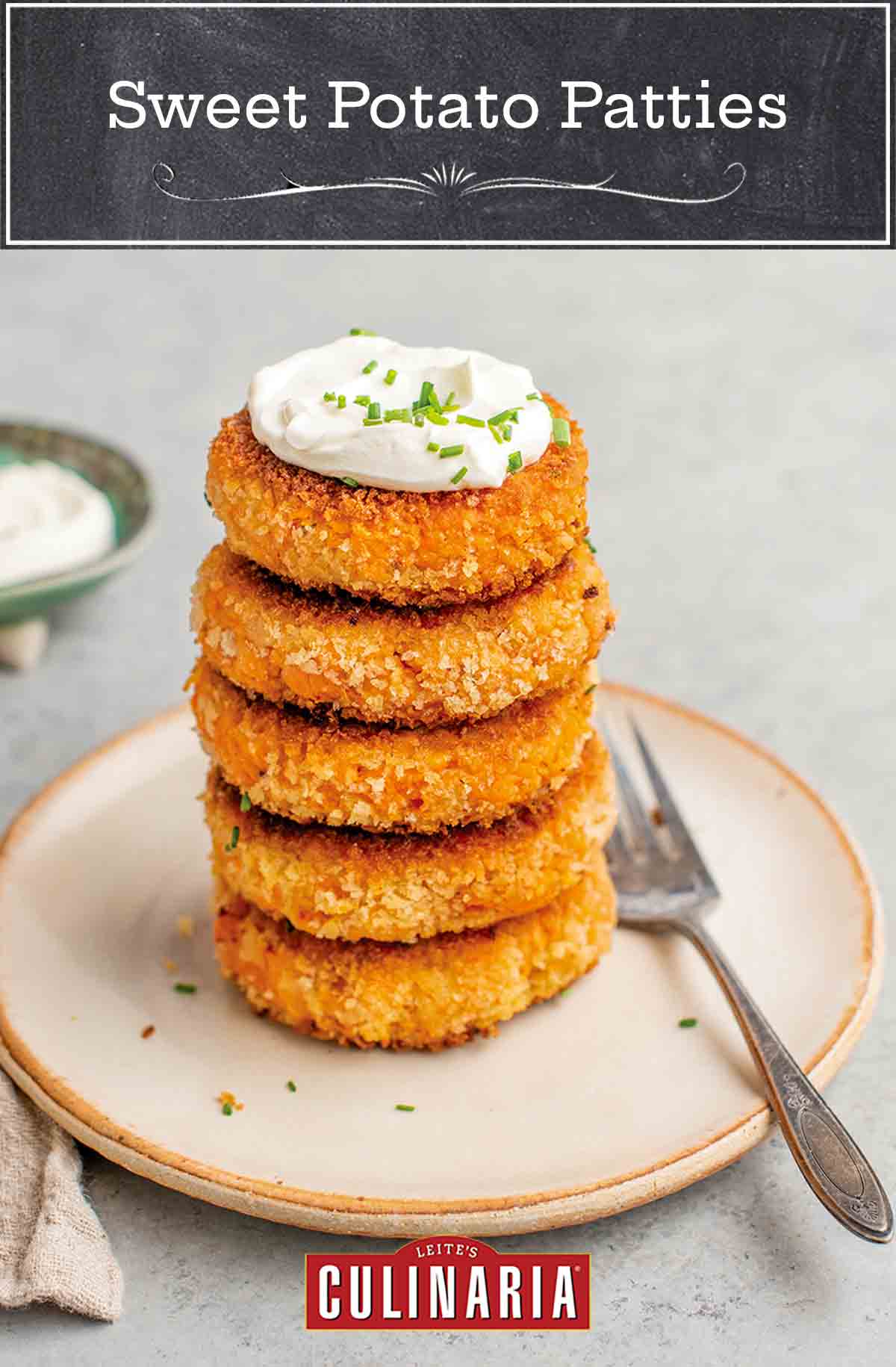 Five sweet potato patties stacked on a plate with a dollop of crème fraîche on top and a fork on the side.