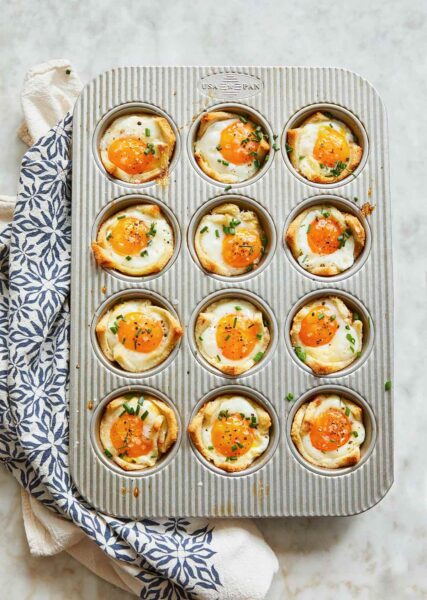 A muffin tin filled with 12 baked egg and toast cups