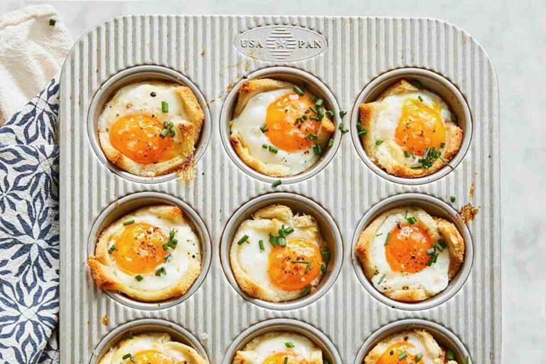 A muffin tin filled with 12 baked egg and toast cups
