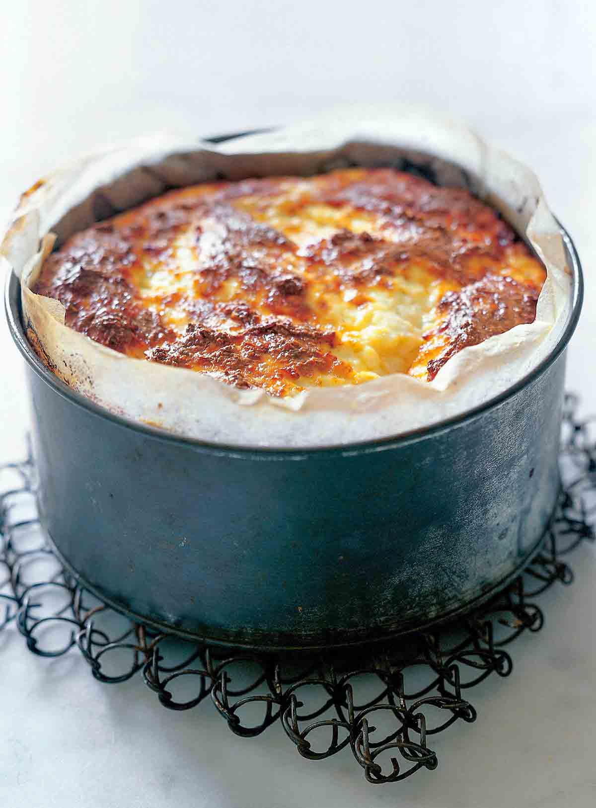 A parchment lined deep baking pan filled with baked ricotta.