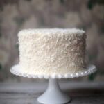 A Brown Betty Bakery coconut cake on a decorative white cake stand.