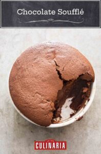 A partially-eaten chocolate souffle in a round white ceramic dish.