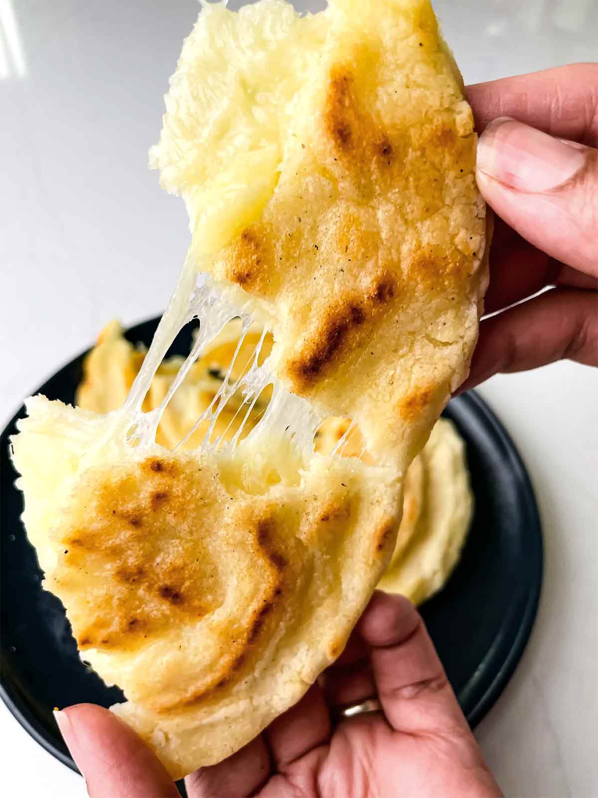 A person tearing a Colombian cheese arepa apart