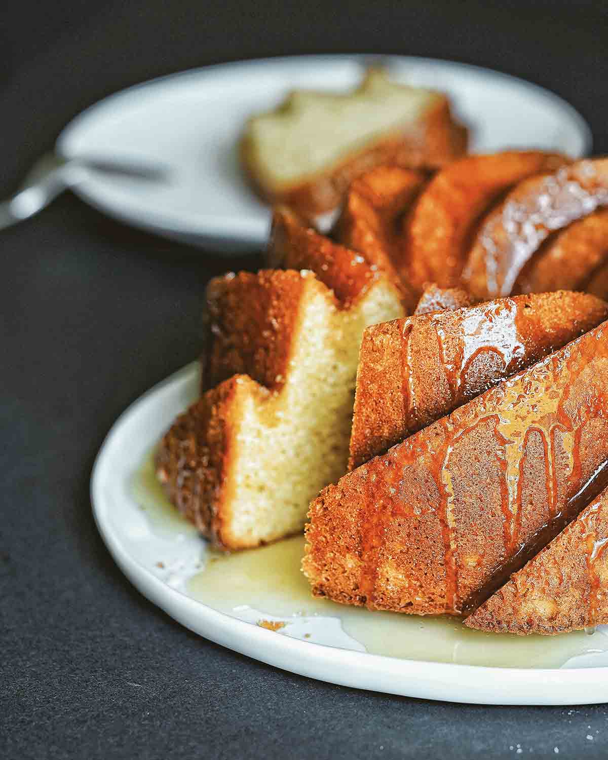 A Kentucky butter cake on a white plate with a slice cut from it on a plate in the background