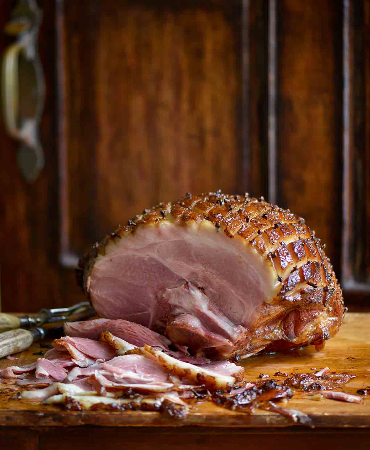 A mustard-glazed ham on a wooden cutting board.