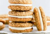 A stack of homemade oatmeal cream pies on a sheet of parchment with a few more scattered around