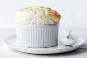 Ramekin with a parmesan souffle on a white plate, spoon, white tablecloth