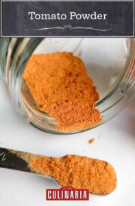 Tomato powder in a jar lying on its side and in a teaspoon beside the jar.