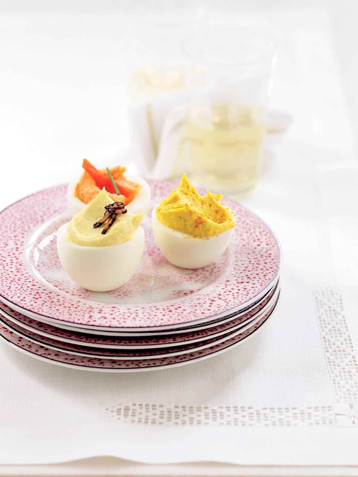 A plate with a trio of deviled eggs - horseradish deviled egg, truffled deviled egg, and smoked salmon deviled egg.