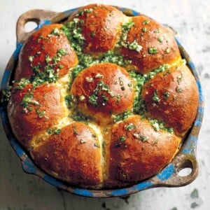 A round dish filled with Ukrainian garlic bread rolls, topped with garlic-parsley oil