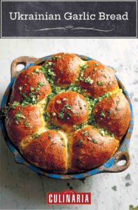 A round dish filled with Ukrainian garlic bread rolls, topped with garlic-parsley oil