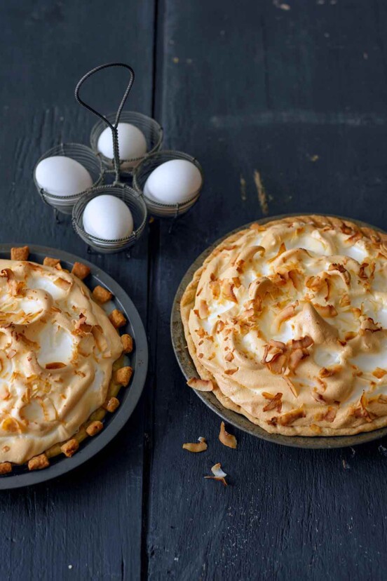 Two coconut cream pies with meringue tops, pastry crusts, and sprinkled with shredded coconut