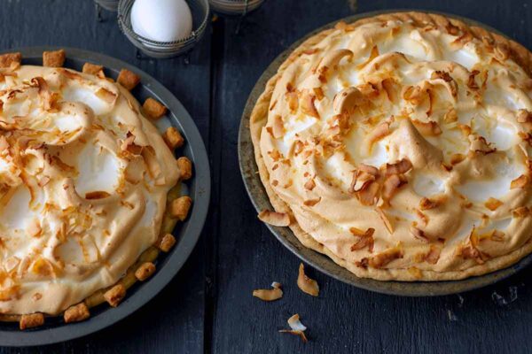 Two coconut cream pies with meringue tops, pastry crusts, and sprinkled with shredded coconut