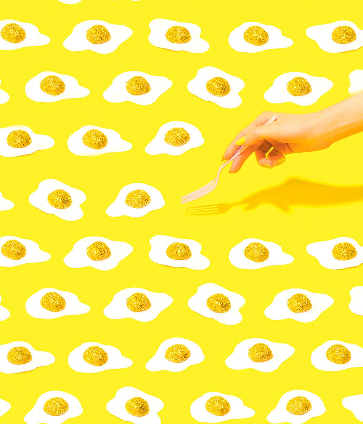 Yellow background with any fried eggs and a woman's hand with a fork