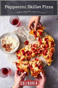 Hands grabbing pieces of skillet pepperoni pizza with two glasses on the side and a bowl of parmesan and pepper flakes