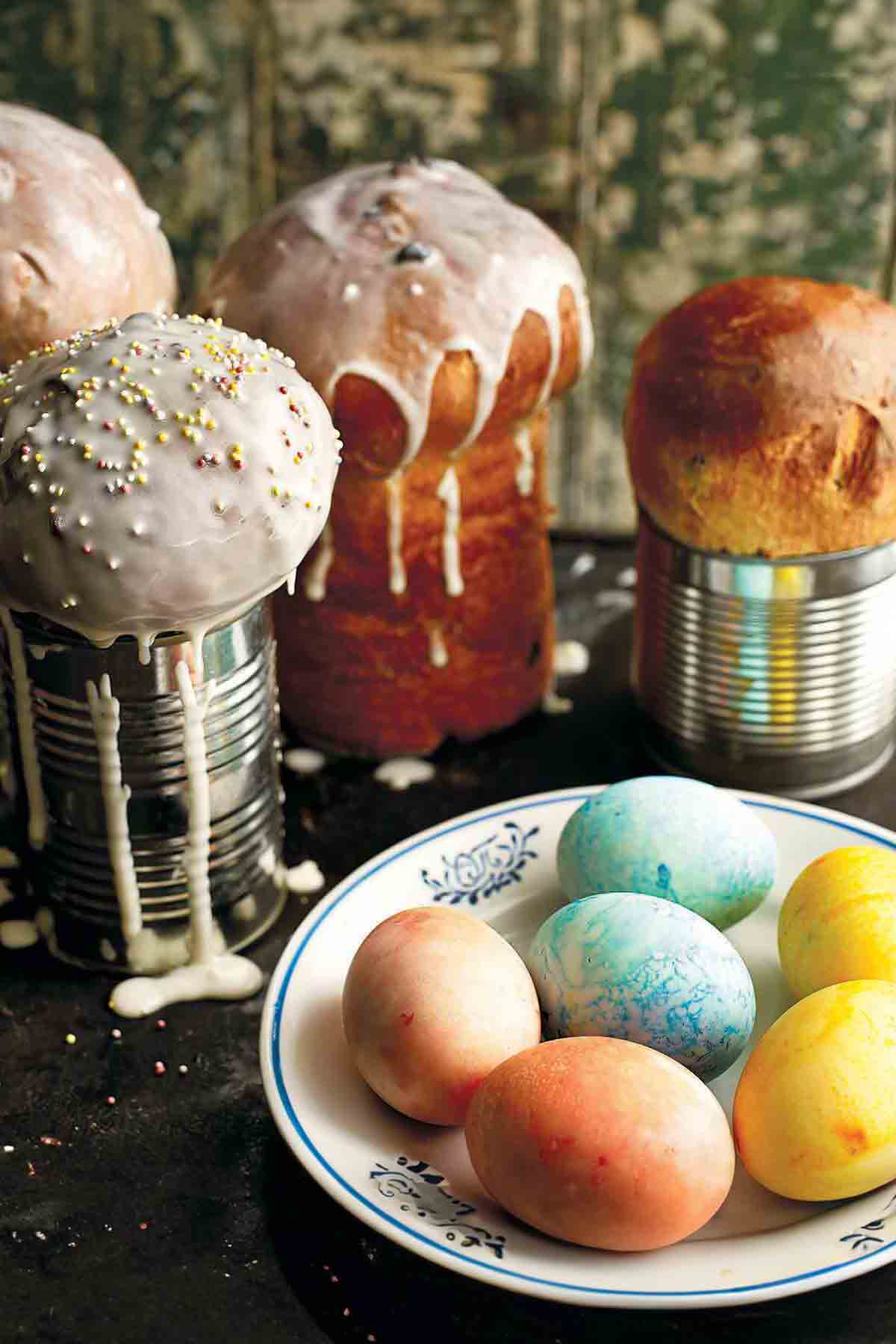 Four loaves of Ukrainian Easter bread, paska, with a bowl of colored eggs in front of them.