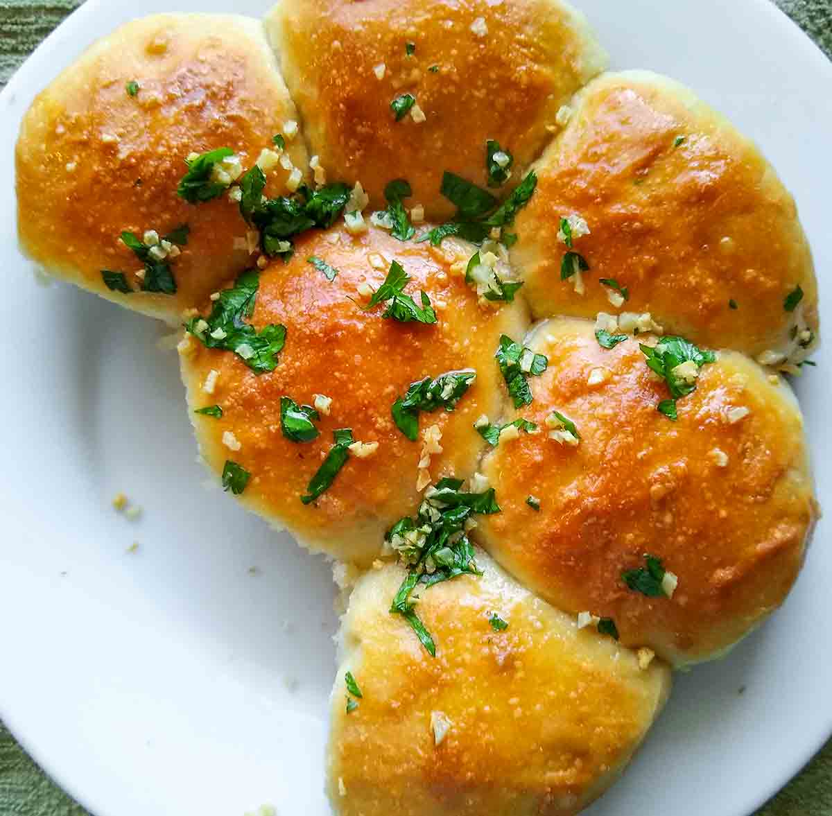 A round plate with Ukrainian garlic bread rolls, topped with garlic-parsley oil