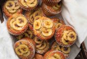 A wooden box filled with banana topped muffins.