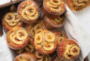 A wooden box filled with banana topped muffins.