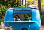 A blue trailer in the woods, with desserts on a shelf.
