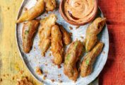 Nine fried avocado dippers on a silver platter with a small dish of chipotle dipping sauce beside them