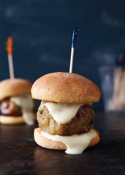 Two ground chicken meatballs on slider buns with a toothpick skewered through them.
